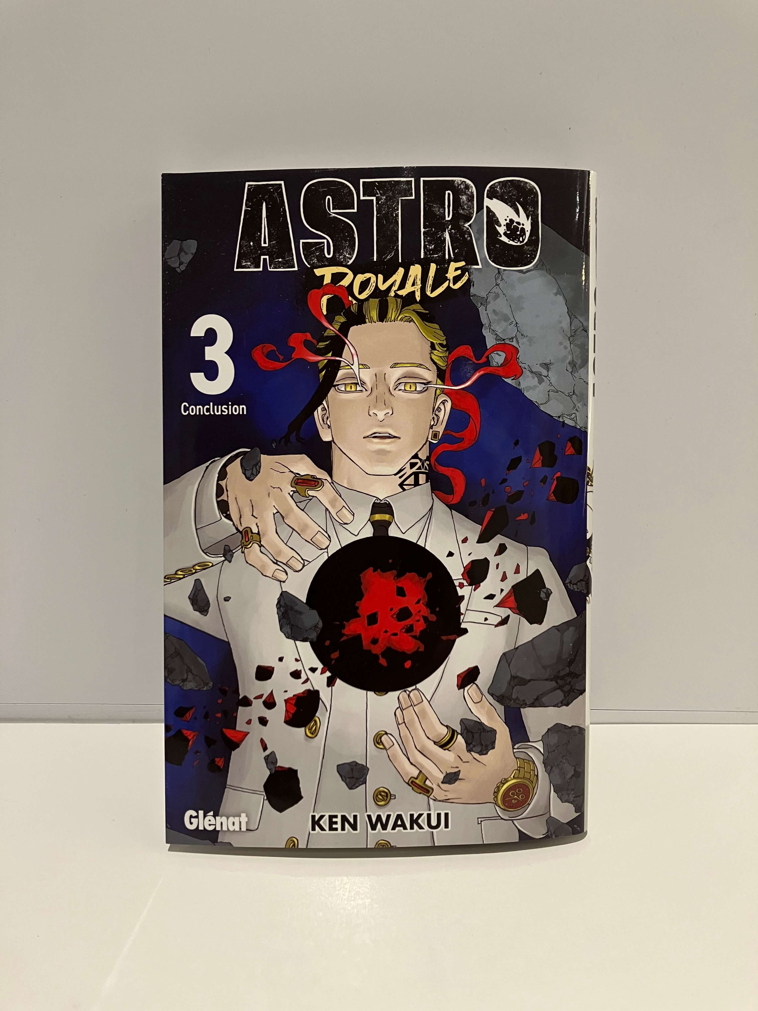 Couverture de  manga Astro Royale tome 3 : un personnage en costume blanc fait léviter une sphère noire entourée de débris sur fond bleu sombre.