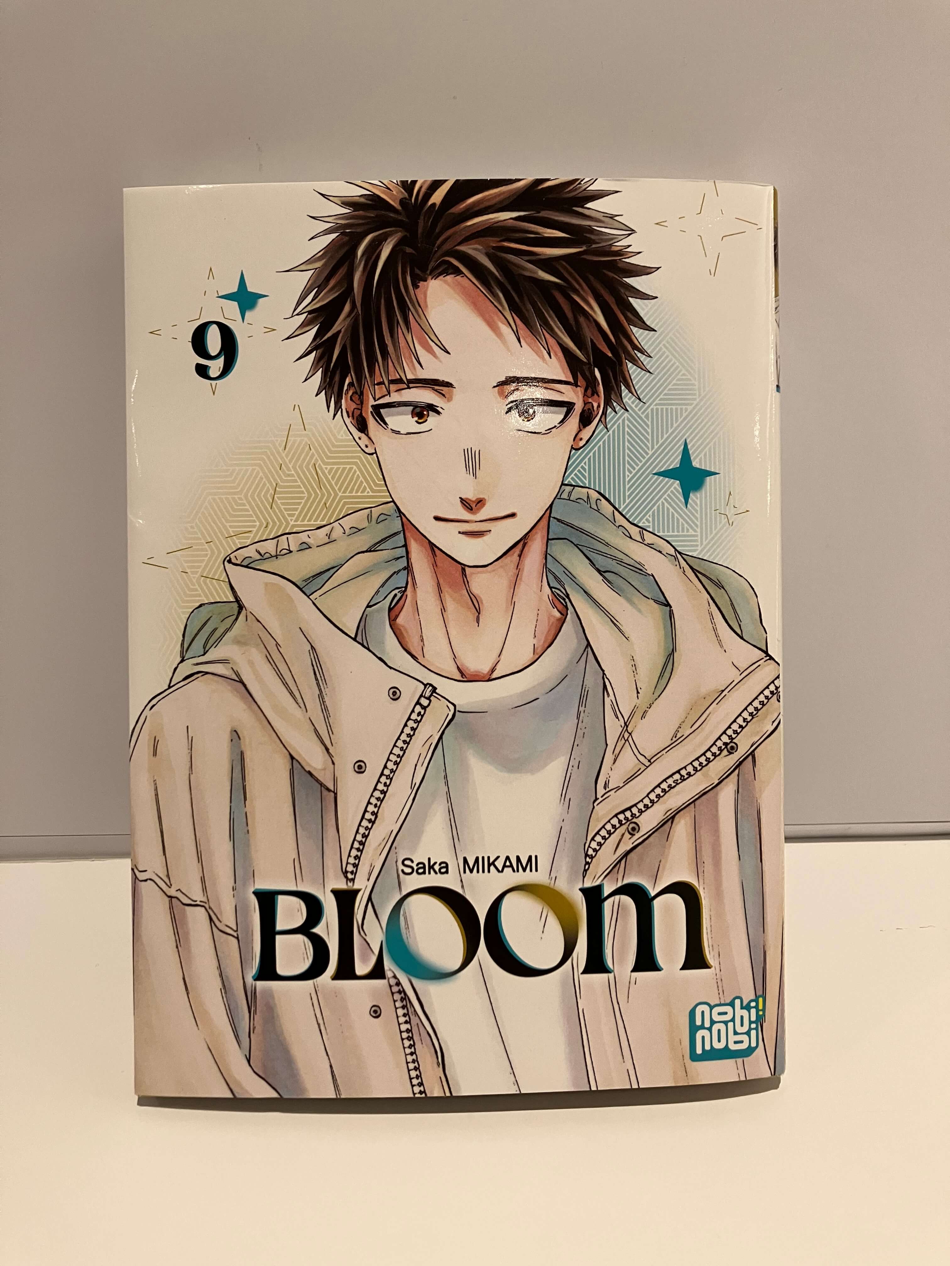 Couverture de Bloom Tome 9 : un garçon souriant sur fond trois couleurs avec les etoiles