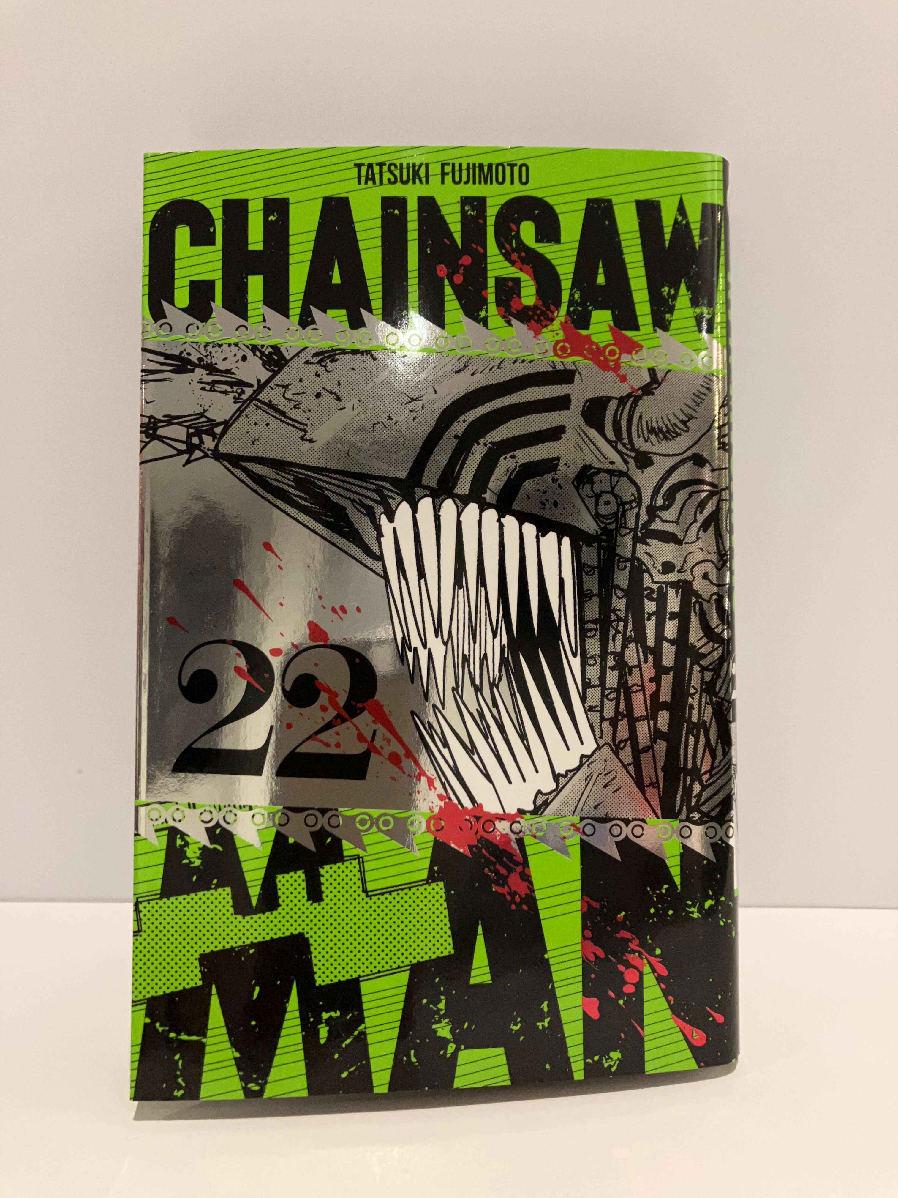Couverture de manga Chainsaw Man Tome 22 édition spéciale : L’illustration met en avant le démon-tronçonneuse vu de profil, avec sa tête mécanique hérissée de longues dents acérées. Le dessin en noir et blanc contraste avec un fond vert vif traversé par le titre en grandes lettres noires. Des éclaboussures rouges et des motifs de chaînes renforcent l’esthétique brutale et énergique propre à la série.