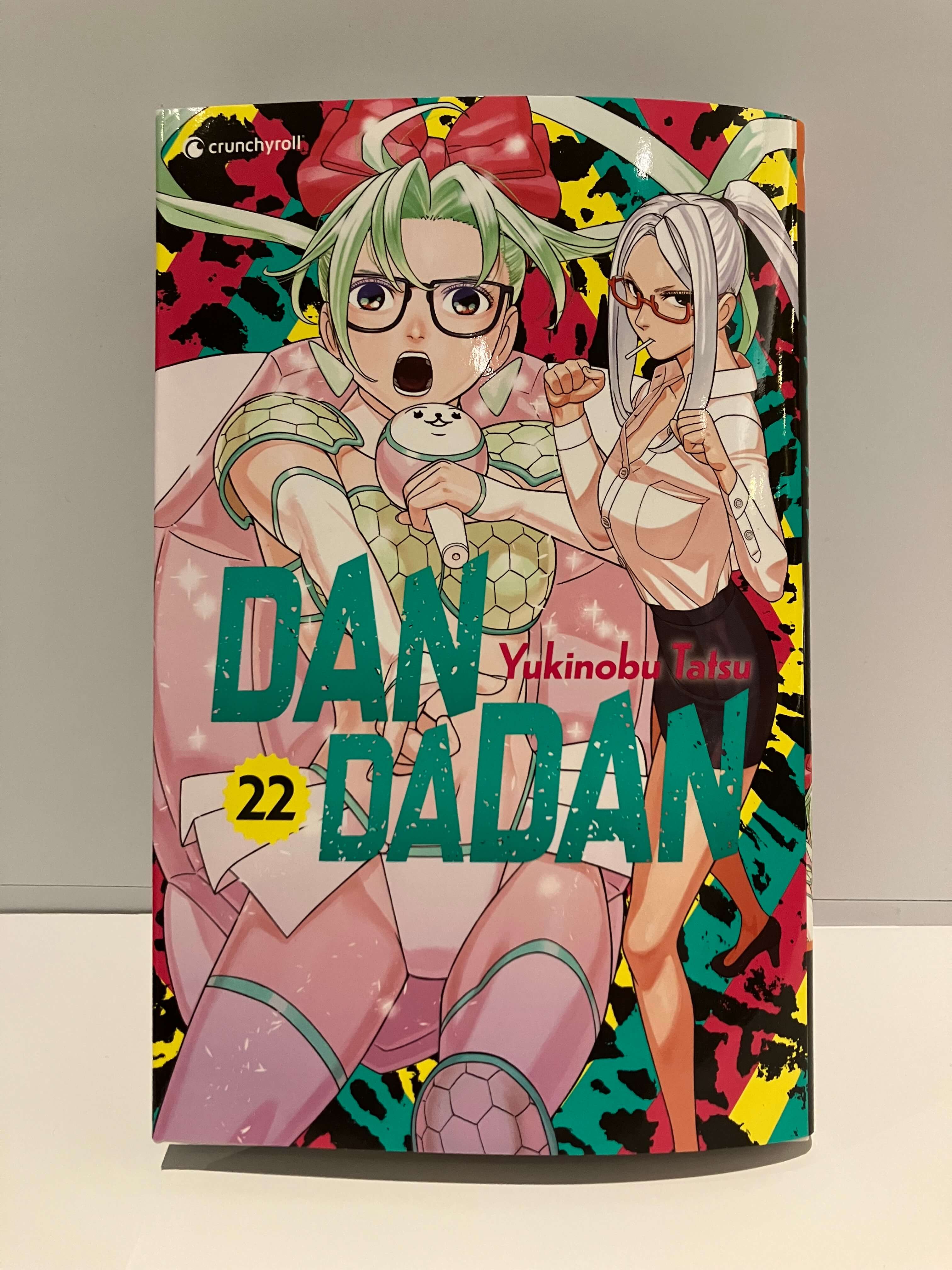 Couverture du manga Dandadan : deux filles avec les lunettes qui sont prêtes à se battre, sur un fond coloré.