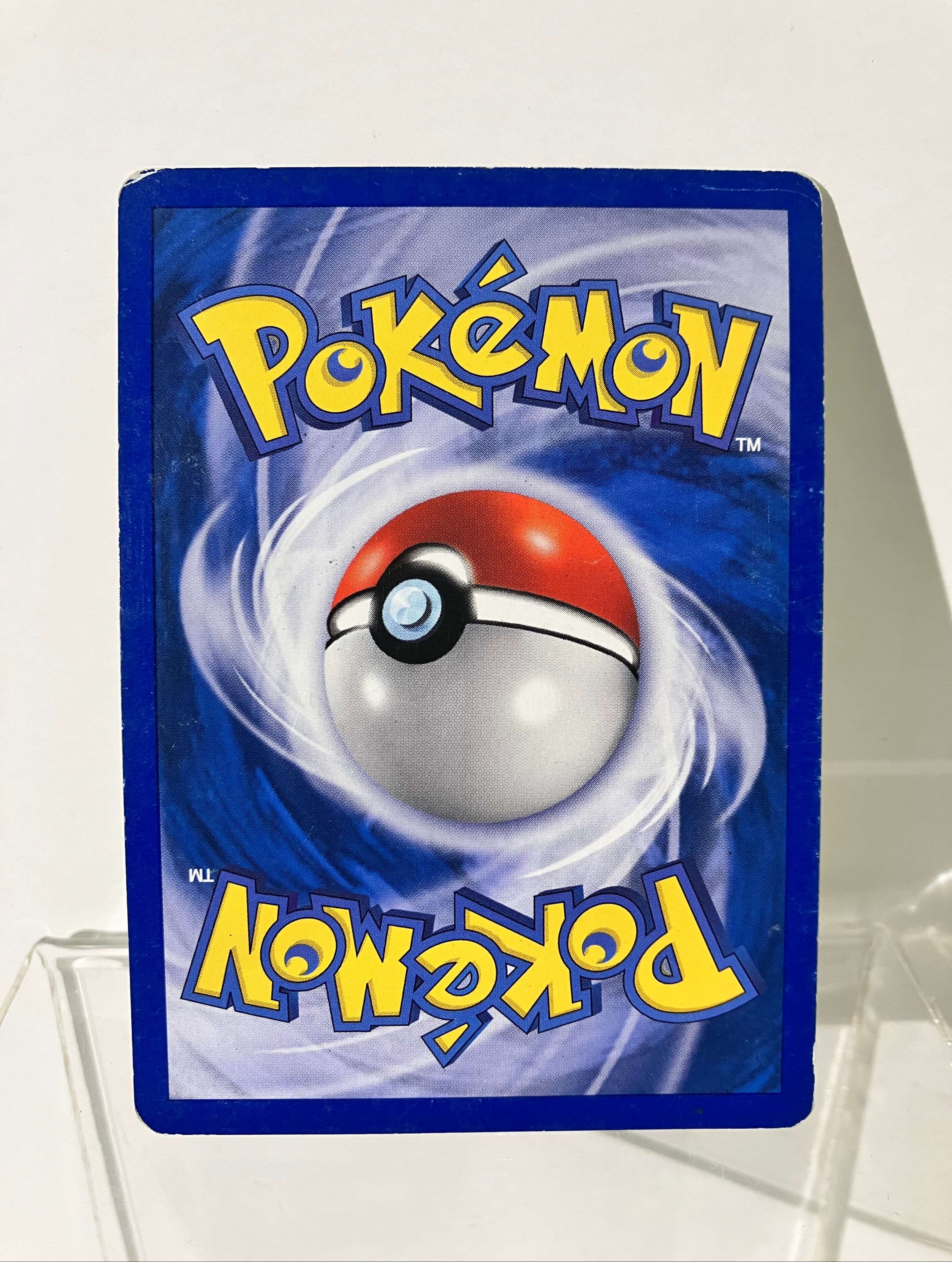 Dos d'une carte Pokémon vintage, Pokéball sur fond bleu avec logo jaune, coin usé.