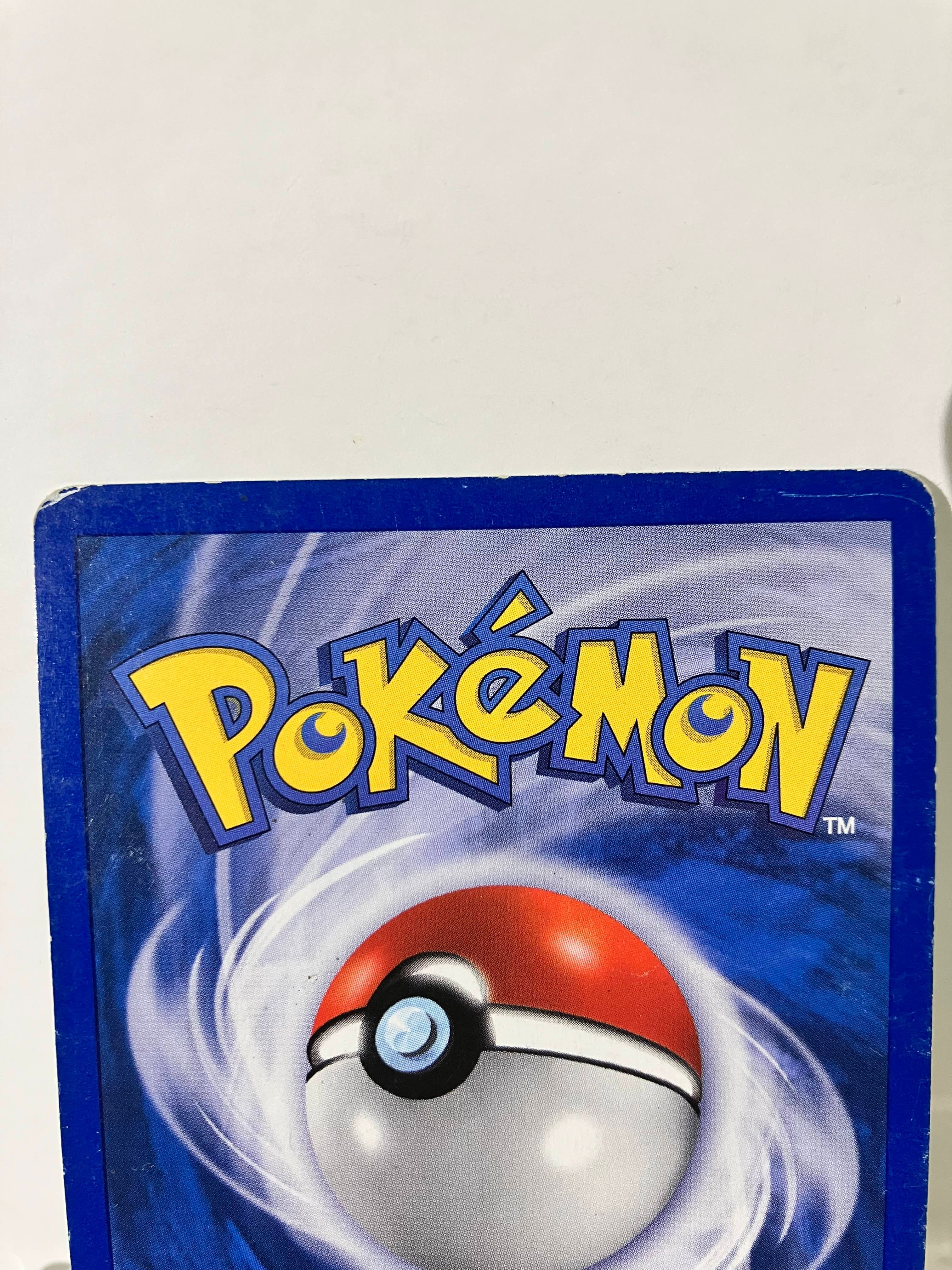 Dos de carte Pokémon avec logo jaune, Pokéball et bordure bleue sur fond blanc