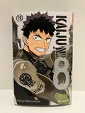 couverture de manga kaiju n°8 tome 16 : un jeune homme en tenue de combat avec masque respiratoire, sur fond de structures industrielles.
