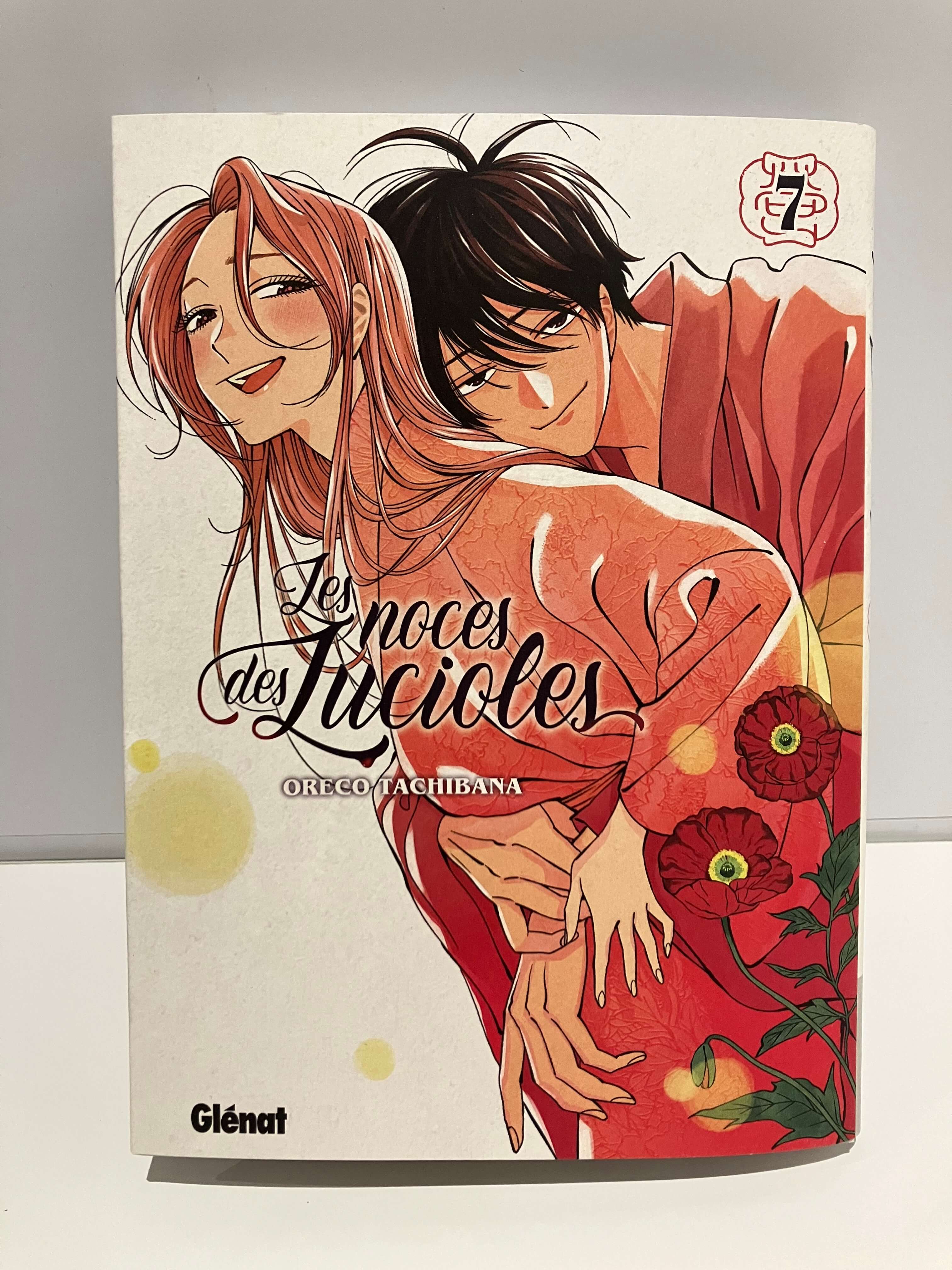 Couverture du manga Les Noces des lucioles : un couple enlacé, la femme en kimono rouge et l’homme derrière elle, sur un fond clair avec des fleurs.