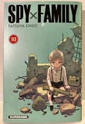 Couverture Spy x Family Tome 10, garçon assis avec fusil, ruines, radio, casque militaire.