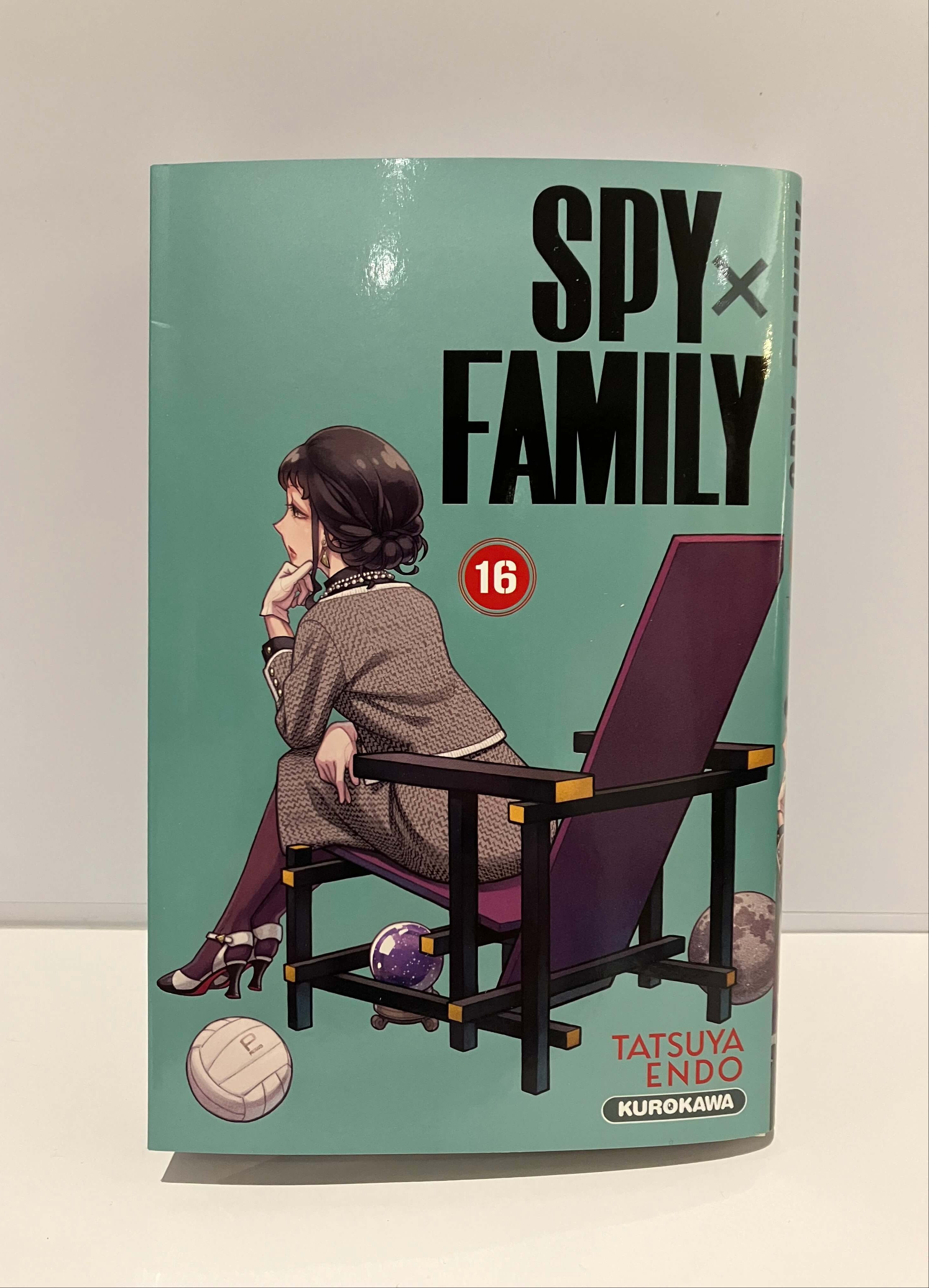 Couverture de Manga Spy x Family : une femme assise dans un fauteuil sur fond vert, entourée de quelques objets, avec le titre en grand en haut.