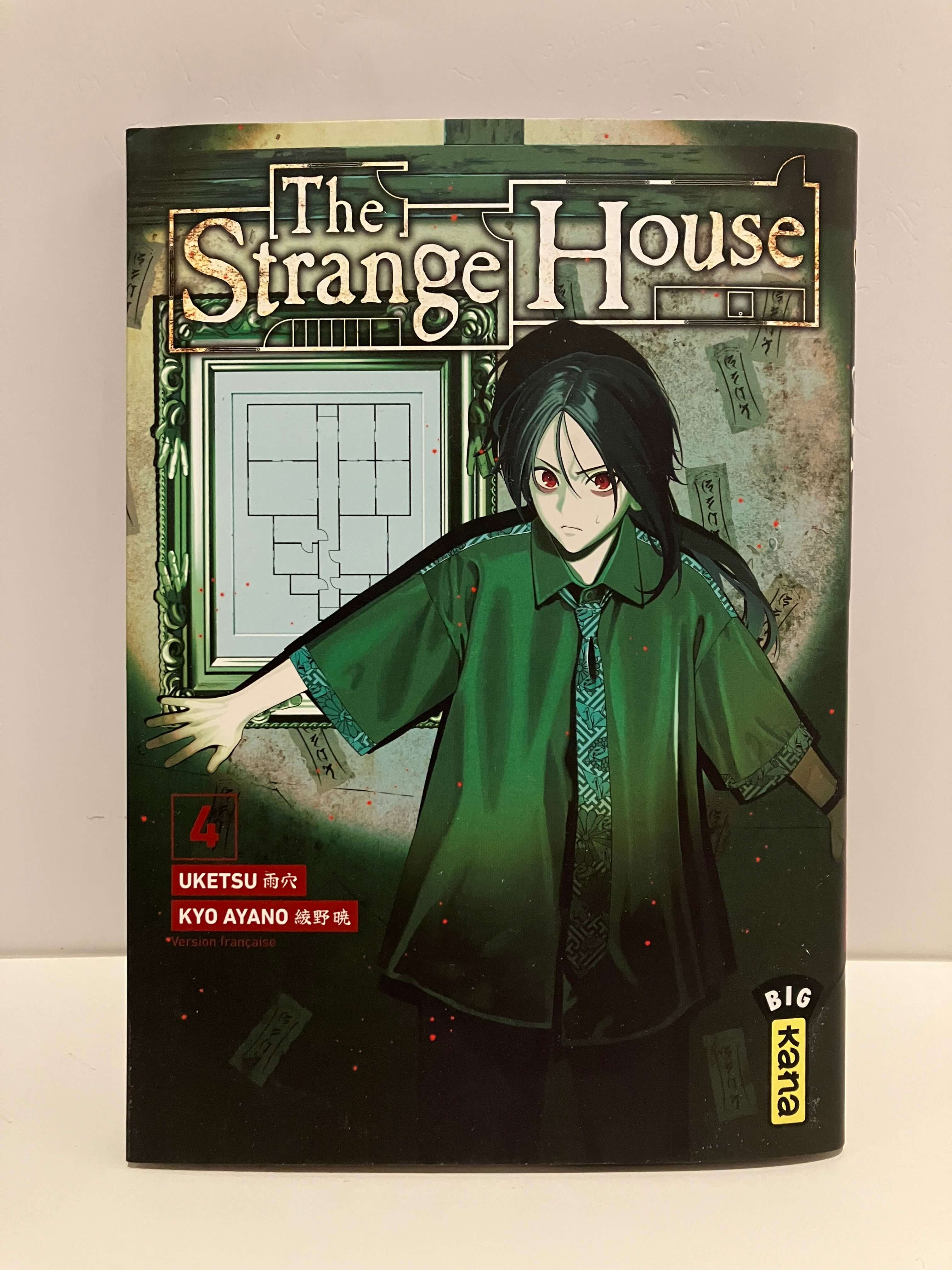 Couverture de manga The Strange House Tome 4 : L’illustration montre un personnage aux longs cheveux noirs et aux yeux rouges, vêtu d’une large tunique verte, dans une posture tendue comme s’il repoussait quelque chose. Derrière lui, on distingue un cadre contenant un plan de maison, avec plusieurs papiers talismans collés autour. Le titre The Strange House apparaît en grand en haut, le numéro 4 et les noms Uketsu et Kyo Ayano figurent à gauche, avec le logo Big Kana en bas à droite.