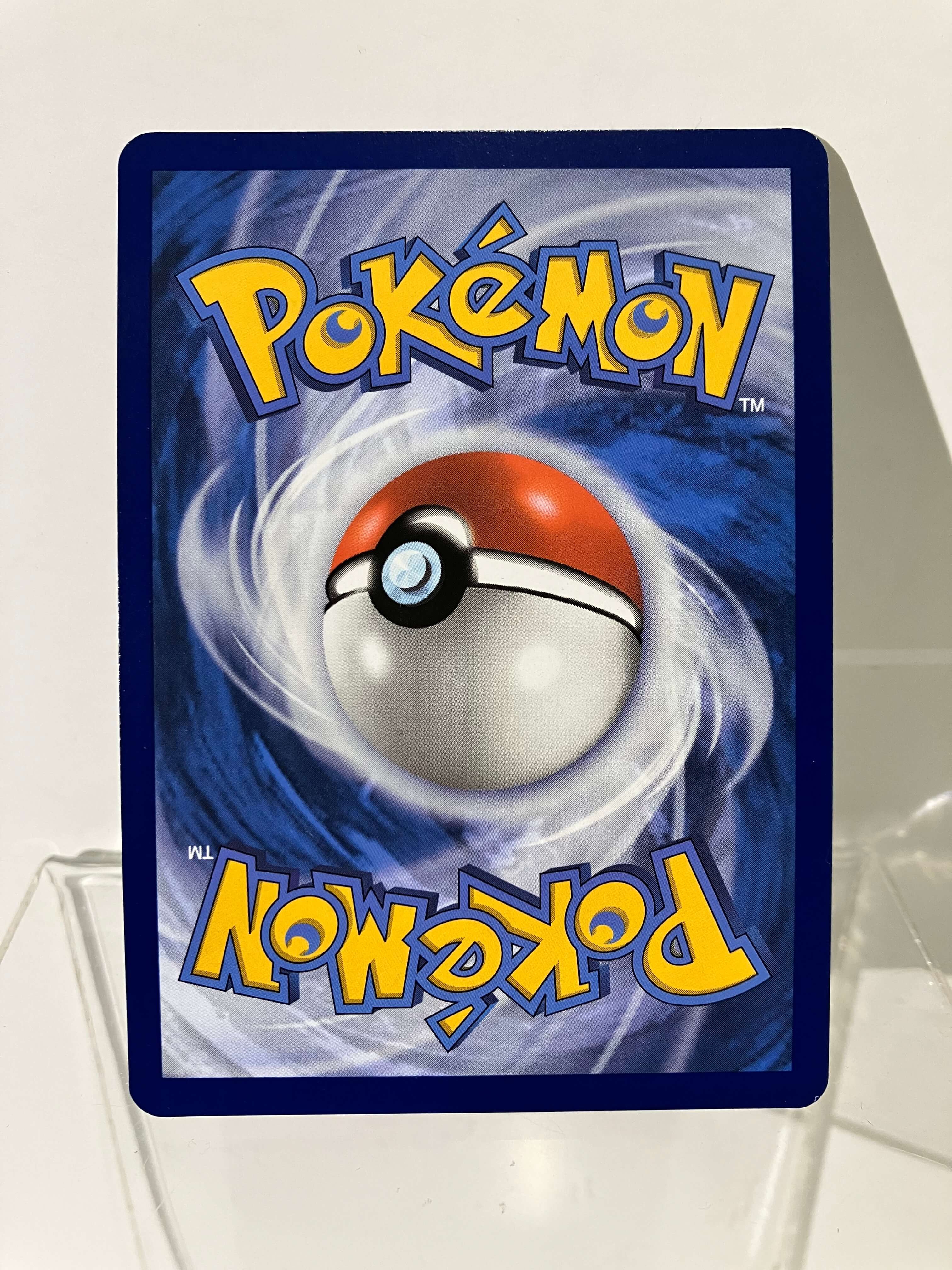 Dos carte Pokémon officielle avec Pokéball sur fond bleu tourbillon, coins arrondis